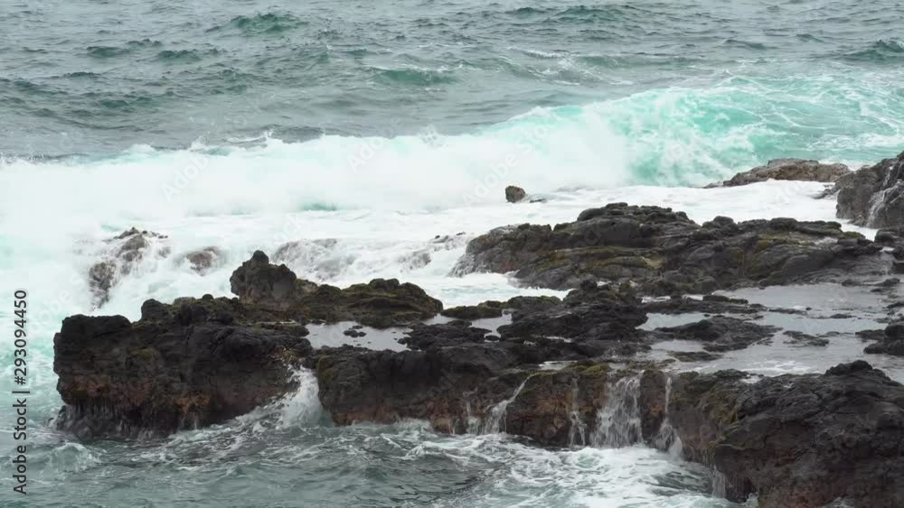 Rough waves crash against jagged rocks near Queen's Bath, Kauai, Hawaii. Rough waves crash against jagged rocks near Queen's Bath, Kauai, Hawaii.