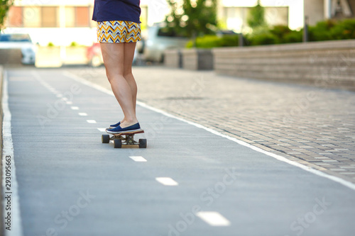 A woman in blue shirt and striped shorts is skateboarding