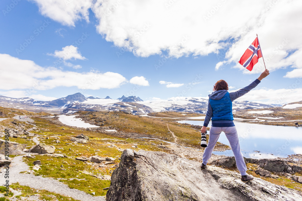 Obraz premium Tourist with camera and flag in Norway mountains