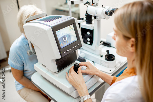 Valokuvatapetti Ophthalmologist examining eyes of a senior patient using digital microscope duri