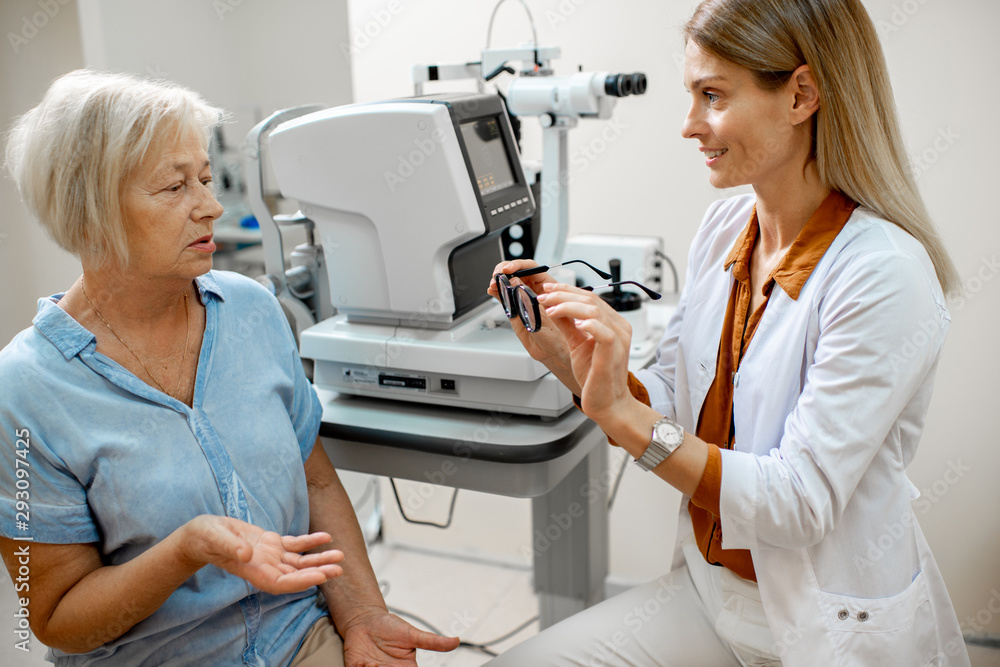 Ophthalmologist offering eyeglasses for vision to a senior woman patient during a medical consultation in the office Ophthalmologist offering eyeglasses for vision to a senior woman patient during a medical consultation in the office