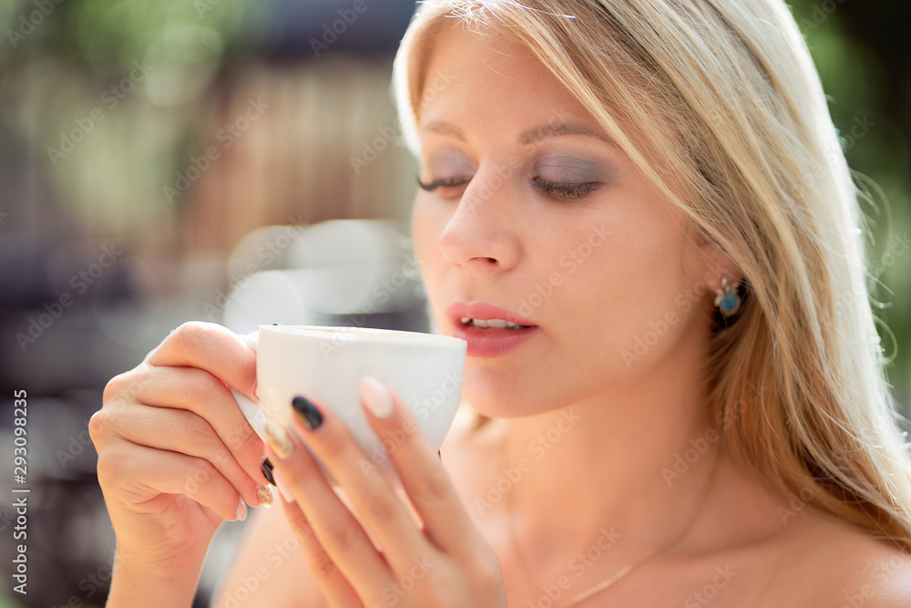 close-up of a beautiful woman with a cup of coffee in the hands in a street cafe. close-up of a beautiful woman with a cup of coffee in the hands in a street cafe.