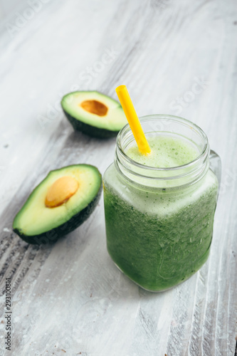 tasty avocado smoothie in jar on white wooden table