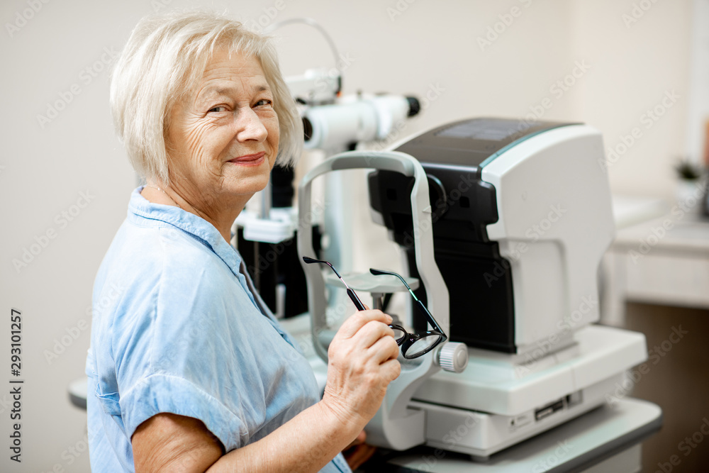 Portrait of a cheerful senior woman as a patient at the ophthalmological office, waiting for eye diagnostics with ophthalmologist Portrait of a cheerful senior woman as a patient at the ophthalmological office, waiting for eye diagnostics with ophthalmologist