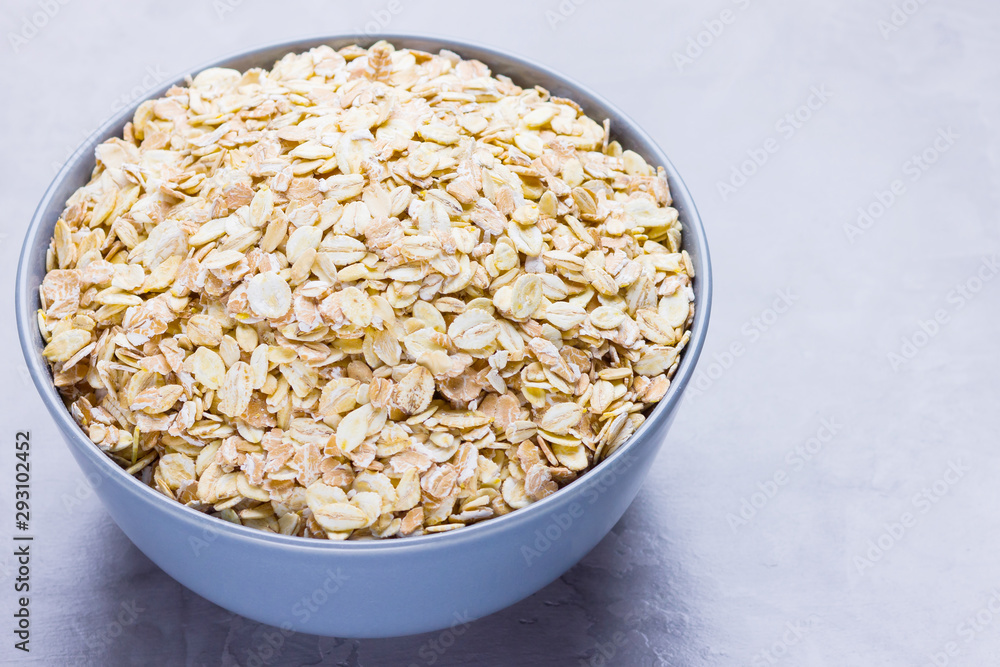 Dry oatmeal in bowl. Oat flakes on cement background. Cereals for making healthy breakfast Dry oatmeal in bowl. Oat flakes on cement background. Cereals for making healthy breakfast