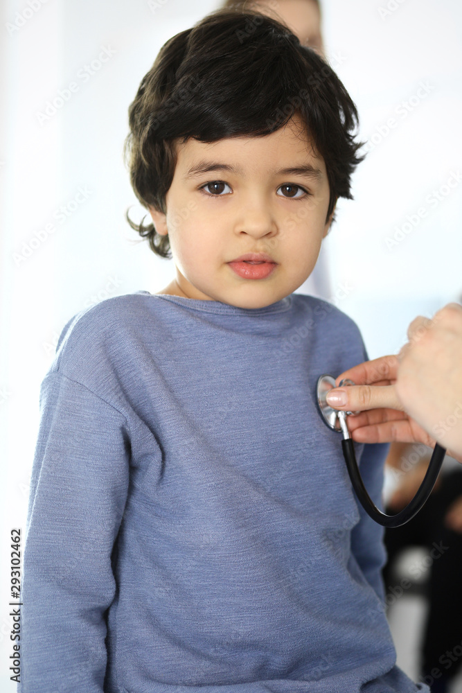 Doctor examining a child patient by stethoscope. Cute arab boy at physician appointment. Medicine and healthcare concept