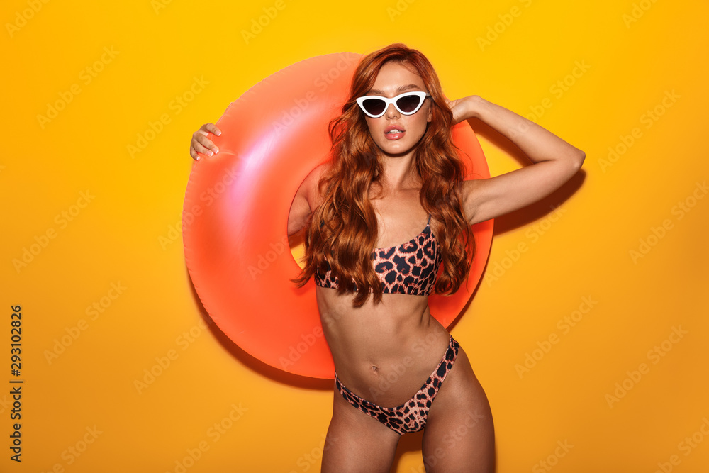 Photo of redhead confident woman wearing leopard bikini and sunglasses holding swim ring Photo of redhead confident woman wearing leopard bikini and sunglasses holding swim ring