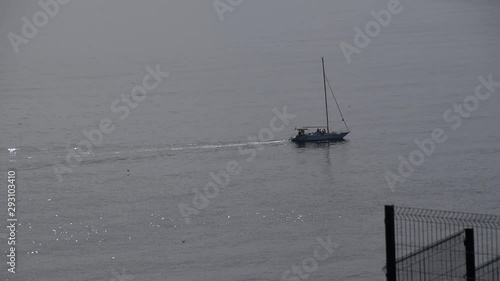 A small yacht with a folded sail floats on the sea