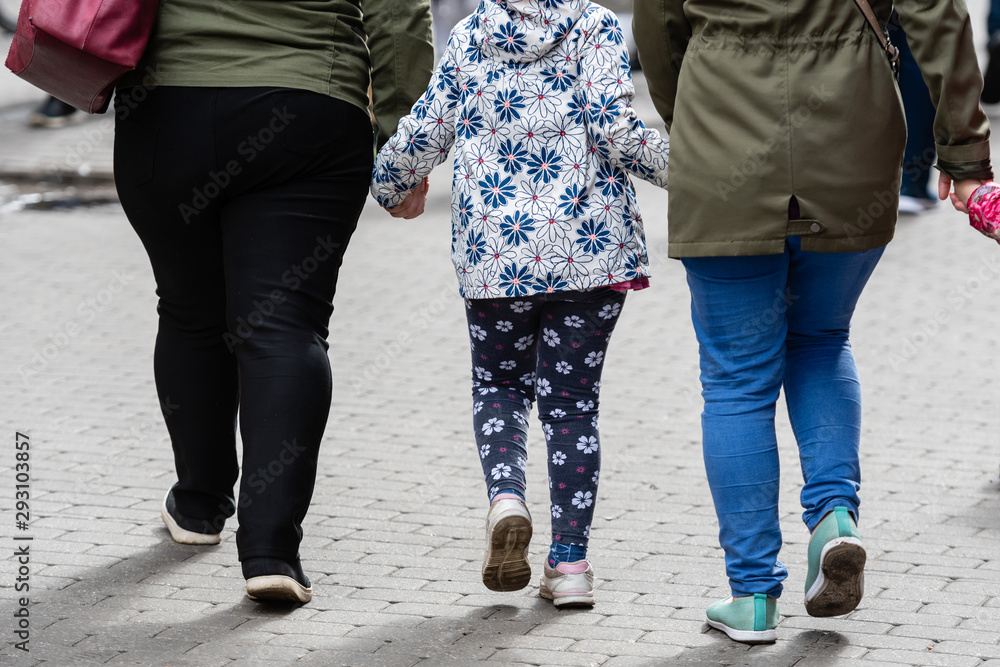 Two women and two children holding hands. Only legs visible. Rear view Two women and two children holding hands. Only legs visible. Rear view