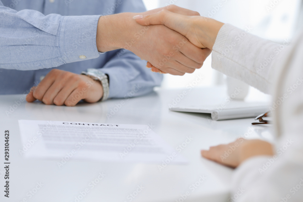 Business people shaking hands at meeting or negotiation after contract discussing. Businessman and woman handshake at office while sitting at the desk. Success concept Business people shaking hands at meeting or negotiation after contract discussing. Businessman and woman handshake at office while sitting at the desk. Success concept