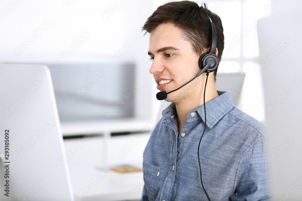 Group of operators at work. Call center. Focus on young man receptionist in headset at customer service. Business concept and casual clothing style Group of operators at work. Call center. Focus on young man receptionist in headset at customer service. Business concept and casual clothing style