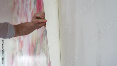 apartment repair and decoration. woman glues photo wallpaper on the wall.