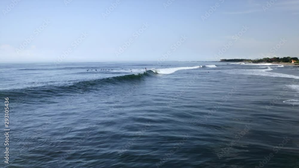 Aerial: People surfing on wave in sea on sunny day - Canggu, Bali Aerial: People surfing on wave in sea on sunny day - Canggu, Bali