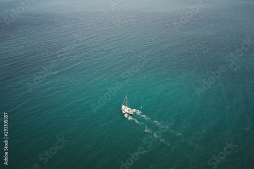 Aerial view of a white boat sailing in the blue sea. Water transportation and summer leisure time activity.