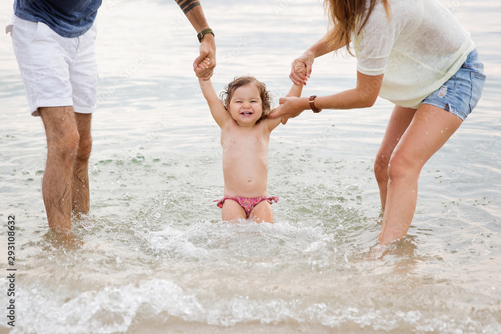 Parents playing in water with laughing toddler girl at beach Parents playing in water with laughing toddler girl at beach