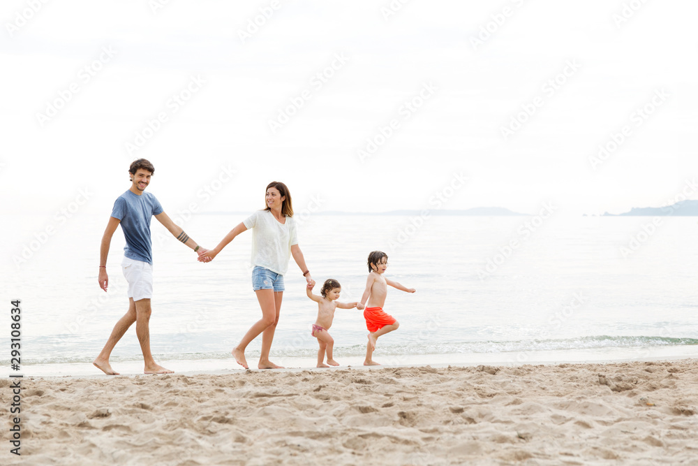 Playful family holding hands and walking in line at beach Playful family holding hands and walking in line at beach