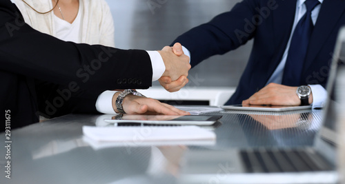 Business people shaking hands after contract signing at the glass desk in modern office. Unknown businessman, male entrepreneur with colleagues at meeting or negotiation. Teamwork, partnership and