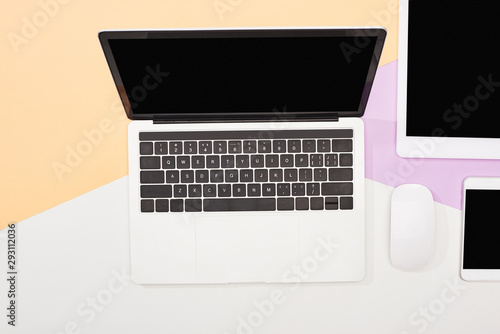 flat lay with laptop, digital tablet, smartphone with blank screen and computer mouse on beige, violet and white background
