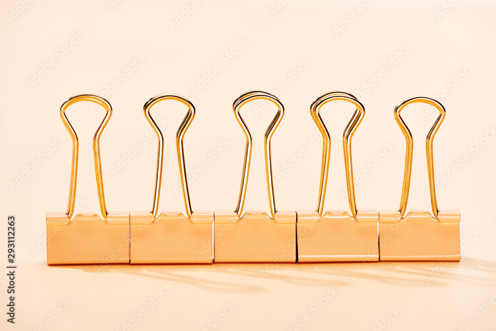 row of paper clips on beige background row of paper clips on beige background