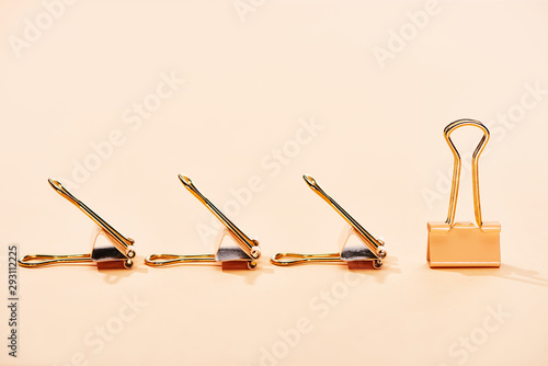 row of paper clips on beige background with copy space