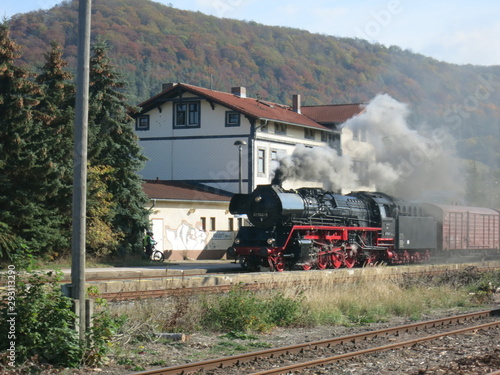 Dampflok mit Güterzug fährt am Empfangsgebäude eines Bahnhofes vorbei