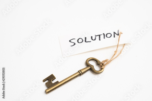 Old vintage brass key with solution word tag on white background