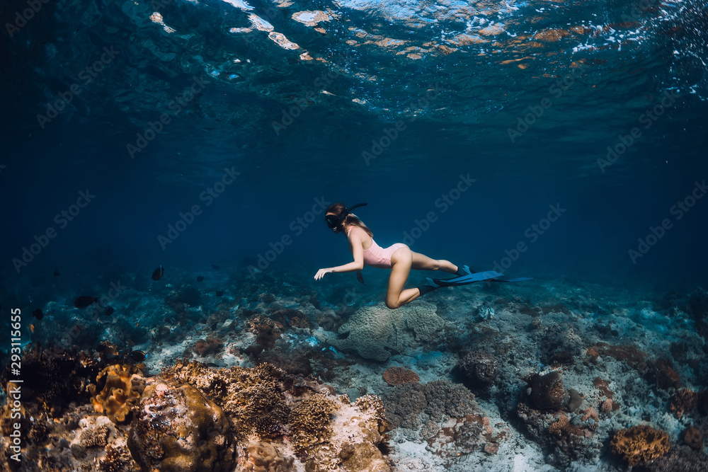 Slim woman freediver glides over bottom in underwater