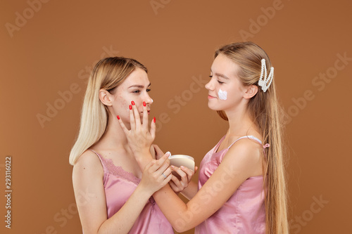 Young girl is upset about her acne and her friend calms and supports her