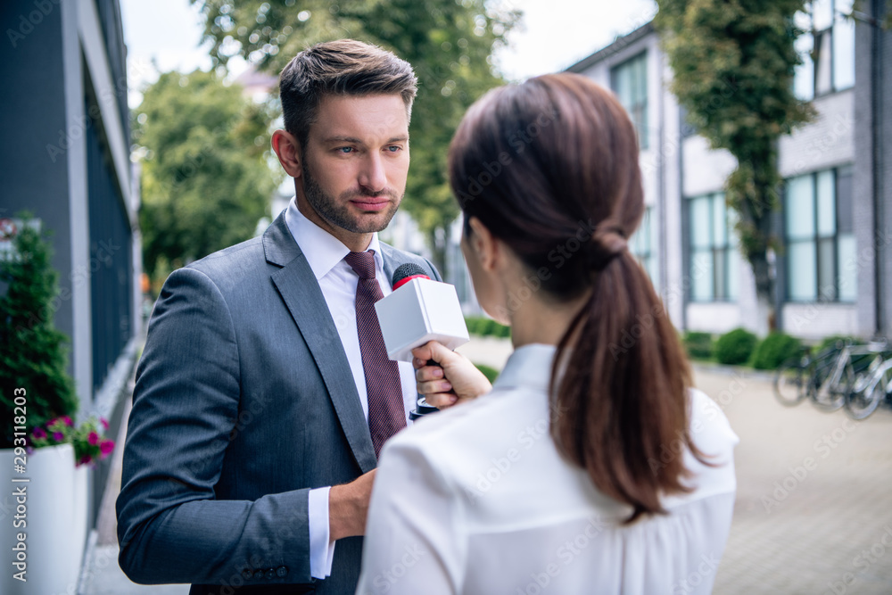 journalist holding microphone and talking with businessman in formal wear journalist holding microphone and talking with businessman in formal wear