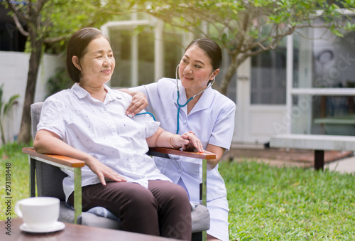 Nurse using stethoscope checking to asian senior woman patient for listening heart rate at home photo