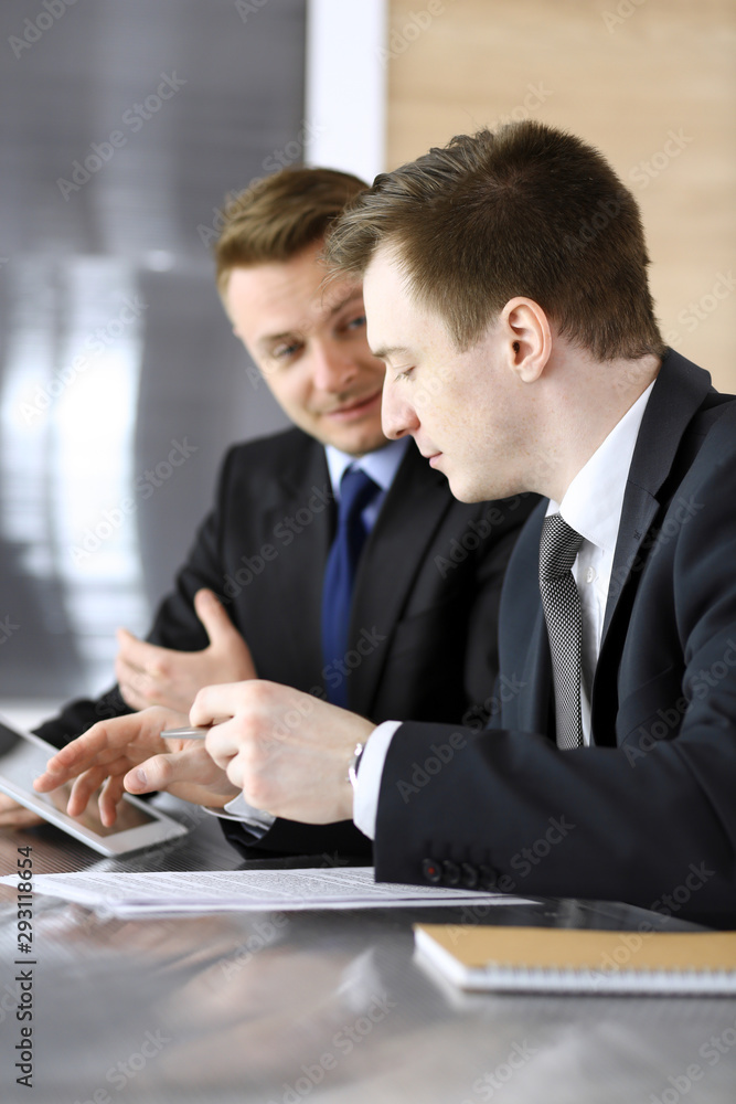 Businessman using tablet computer and work together with his colleague or partner at the glass desk in modern office. Unknown business people at meeting. Teamwork and partnership concept Businessman using tablet computer and work together with his colleague or partner at the glass desk in modern office. Unknown business people at meeting. Teamwork and partnership concept