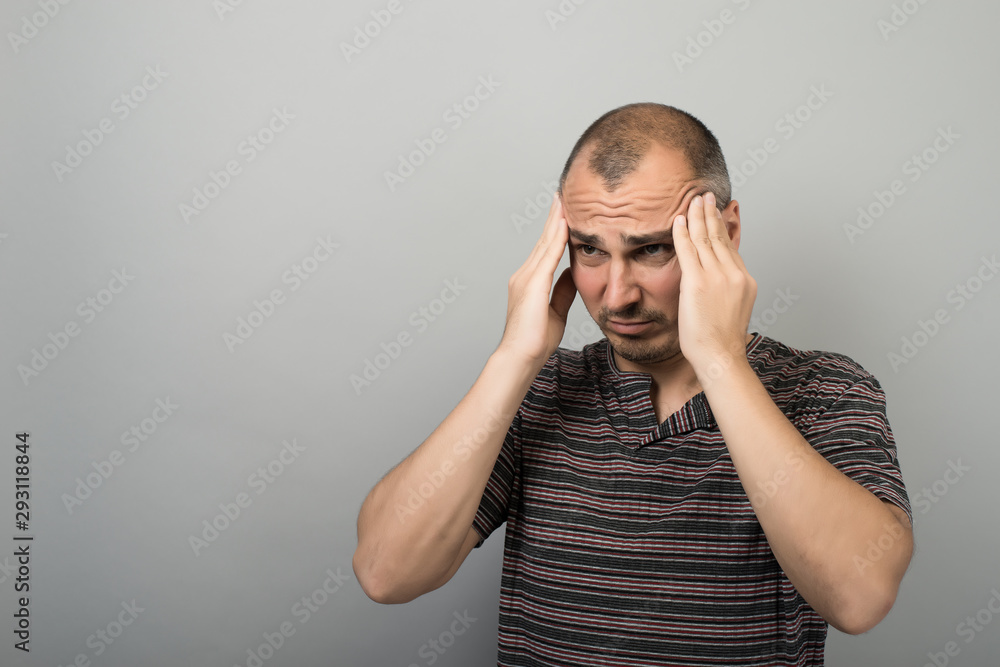 Tensed bearded young man touching his temples and having headache Tensed bearded young man touching his temples and having headache