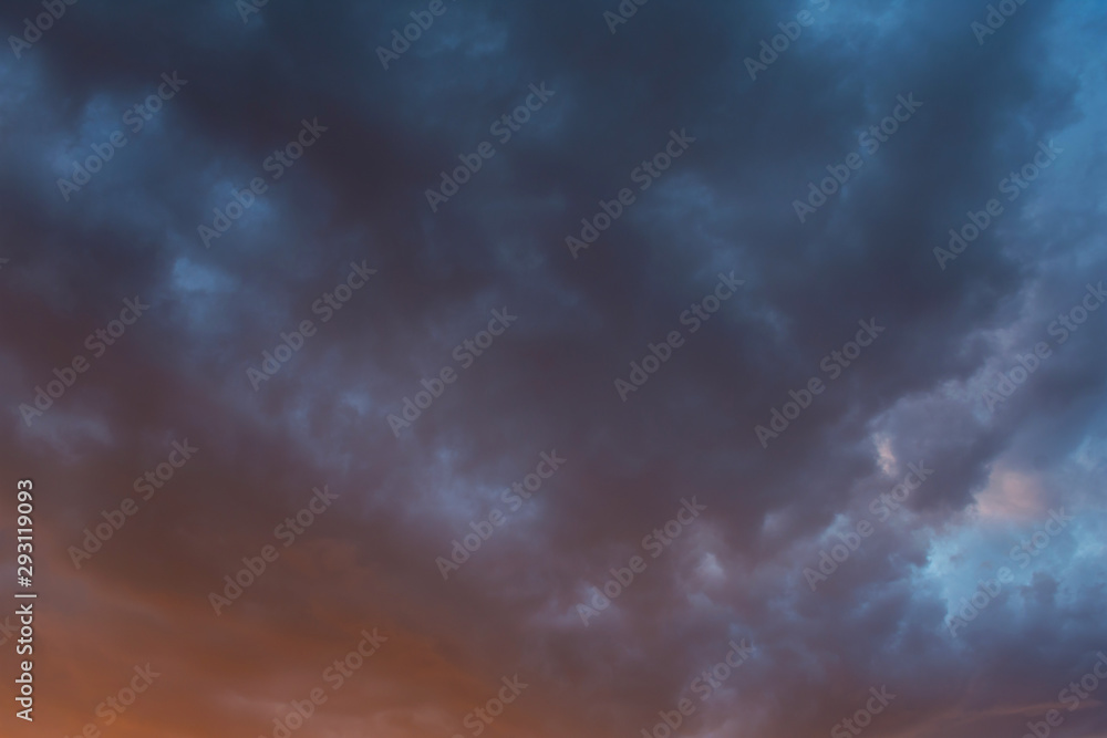 Storm clouds at sunset in orange and blue colors