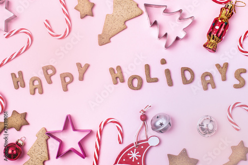 Christmas Concept Background Gingerbread Cookies Candy Canes Christmas Red and Silver Balls and Cookies Mold on Pink Background Happy Holidays Gingerbread in Shape of Letters Top View Flat lay Toned