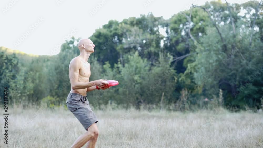 Slow Motion Of young slim athletic man with bare torso catching and throwing frisbee. Active several friends Playing Frisbee in park. Group of active friends spending time together outdoors. Slow Motion Of young slim athletic man with bare torso catching and throwing frisbee. Active several friends Playing Frisbee in park. Group of active friends spending time together outdoors.
