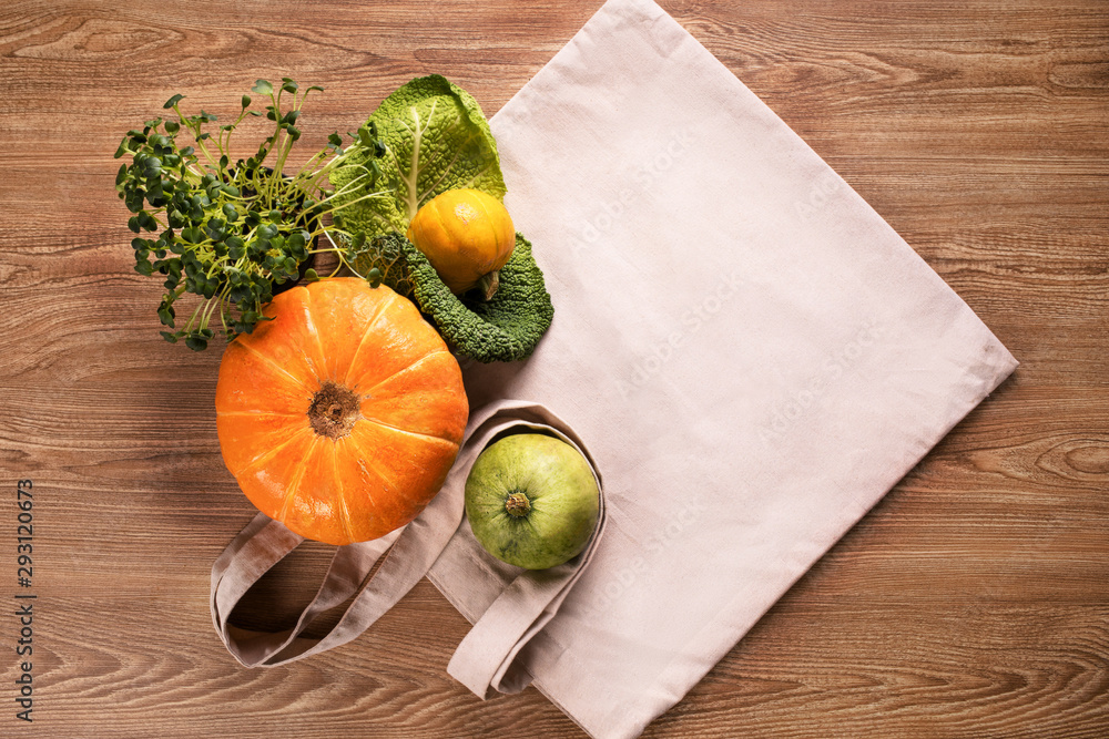 Fresh vegetables, pumpkins, cabbage leaf with green grass in pot, flatlay on eco bag and wooden background table Fresh vegetables, pumpkins, cabbage leaf with green grass in pot, flatlay on eco bag and wooden background table