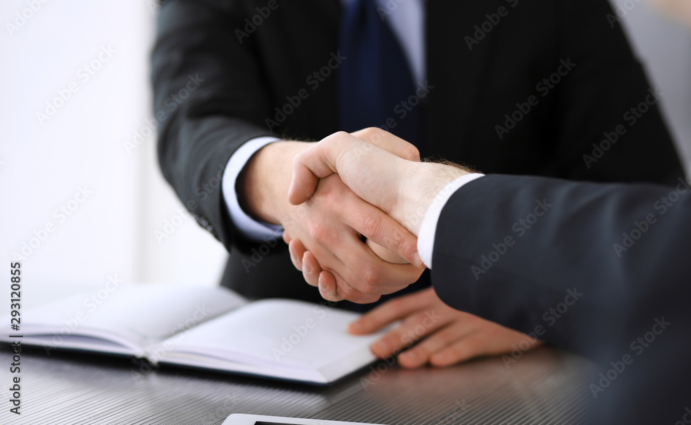 Businessman shaking hands with his colleague or partner above the glass desk in modern office, close-up. Unknown business people at meeting. Teamwork, partnership and handshake concept Businessman shaking hands with his colleague or partner above the glass desk in modern office, close-up. Unknown business people at meeting. Teamwork, partnership and handshake concept