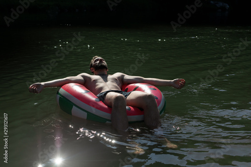 Canvas-taulu bearded man of caucasian nationality sleeps on inflatable watermelon pool float