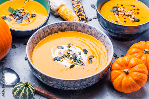 close-up view of pumpkin soup puree in bowls, corn and pumpkins on table