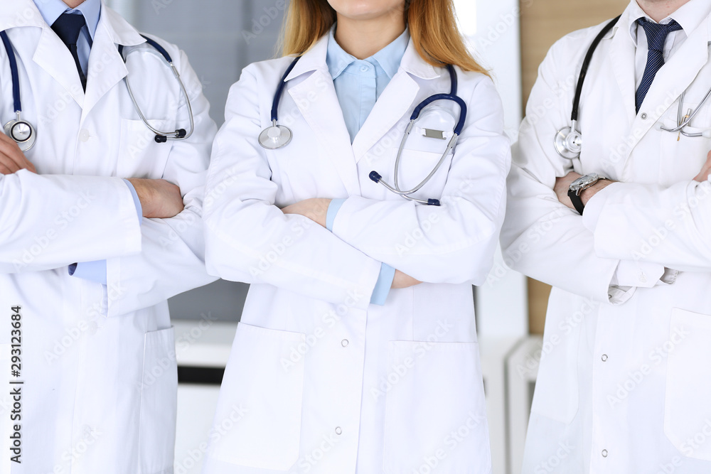 Group of modern doctors standing as a team with arms crossed in hospital office, close-up. Physicians ready to examine and help patients. Medical help, insurance in health care, best treatment and Group of modern doctors standing as a team with arms crossed in hospital office, close-up. Physicians ready to examine and help patients. Medical help, insurance in health care, best treatment and