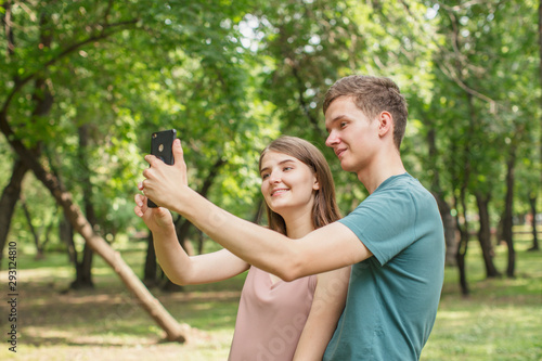 Young man and his girlfriend taking selfie in the park