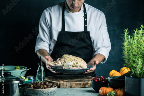 Fotografia partial view of male chef in apron preparing stuffed duck