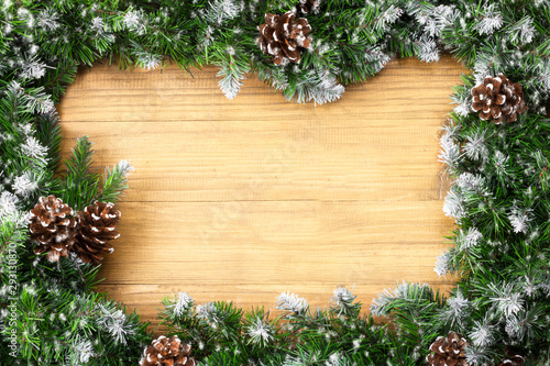  Arch shaped Christmas border composed of snow-covered fir branches and cones on christmas wooden background. Winter holiday background. Great for New year cards, banners, headers, party posters. 