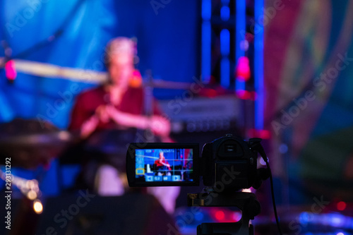 Video camera recording ethnic open air concert. Man with tank drum or hang on blurry abstract bokeh background