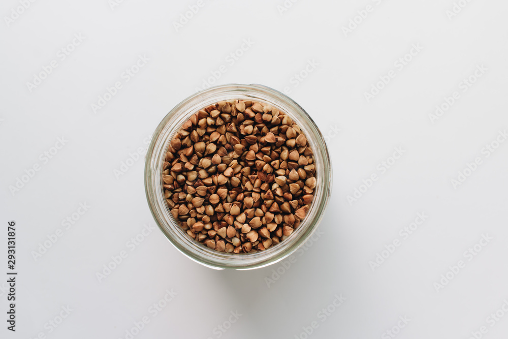Raw buckwheat in glass on white background, heathy food, diet Raw buckwheat in glass on white background, heathy food, diet