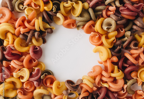 Pile of uncooked bright macaroni on white background