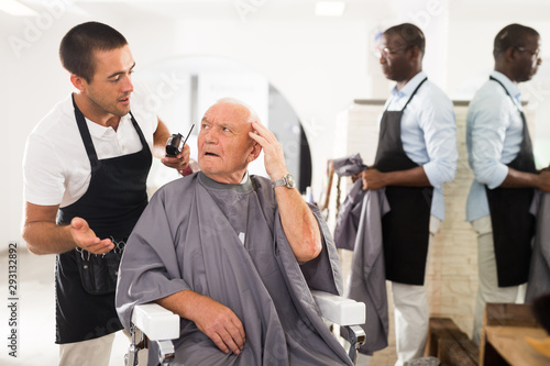Shocked elderly man with confused hairdresser