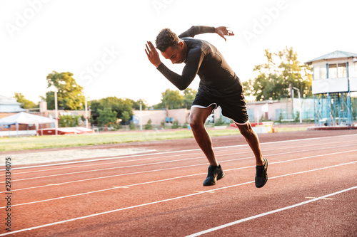 Image of active african american man running on sports stadium