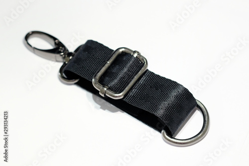 Metal banner  carabiner and half ring with a shoulder strap on a white background. Samples of handbags in dark nickel on a black belt.