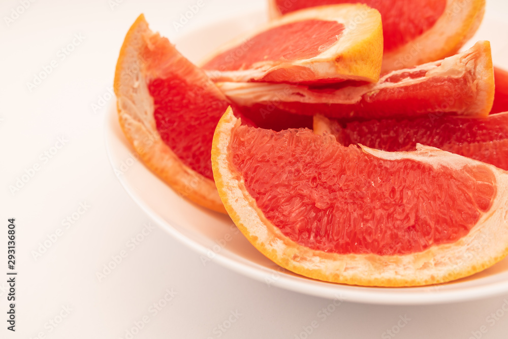 Fresh ripe juicy grapefruit on white plate on white background. Fresh ripe juicy grapefruit on white plate on white background.